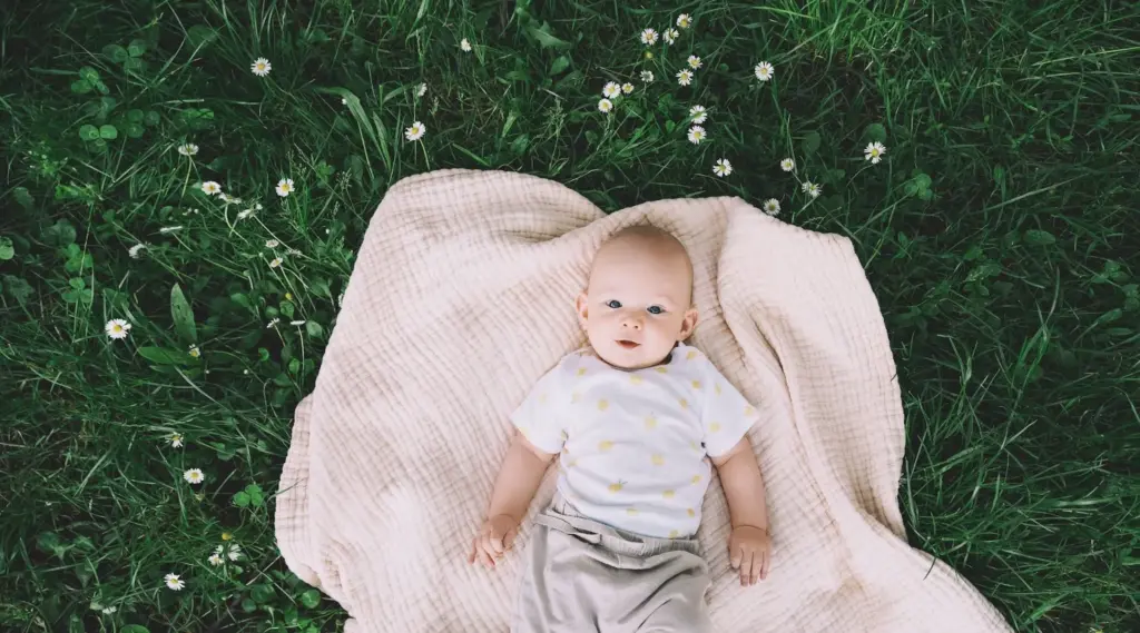 Baby lying in the grass on a blanket