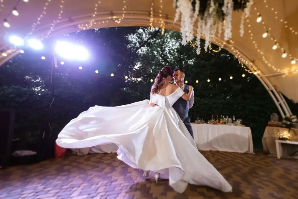 Bride and groom dancing under a canopy of string lights