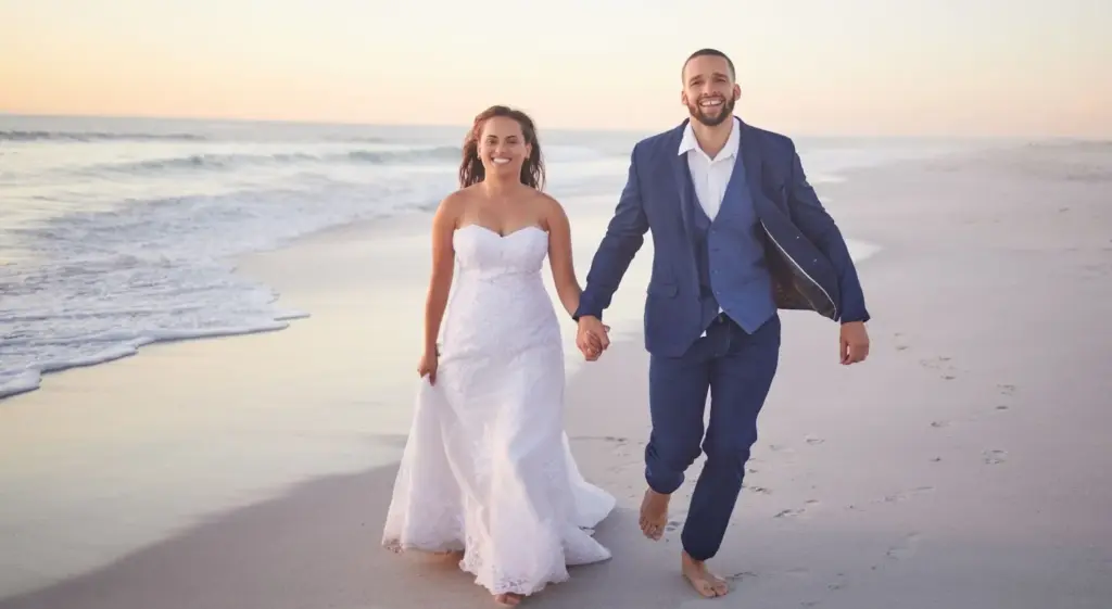 Bride and groom walking barefoot along the shoreline