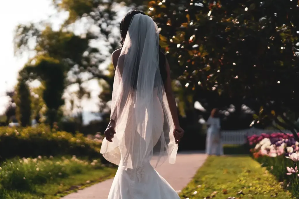 Bride walking, veil trailing through flowers