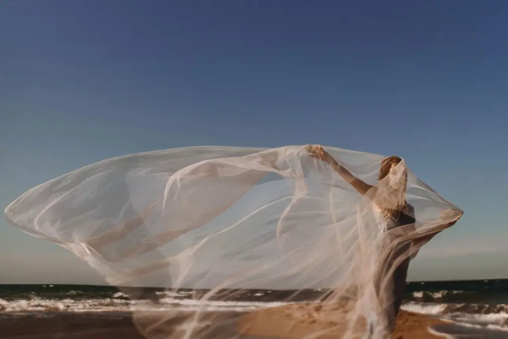 Bride’s veil blowing in the breeze beside the lake