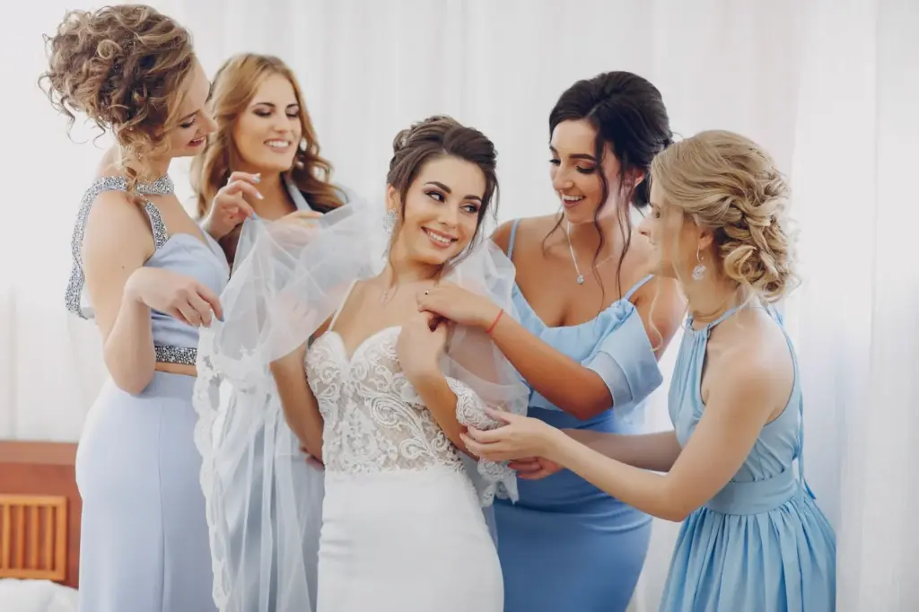 Bridesmaids helping the bride into her dress