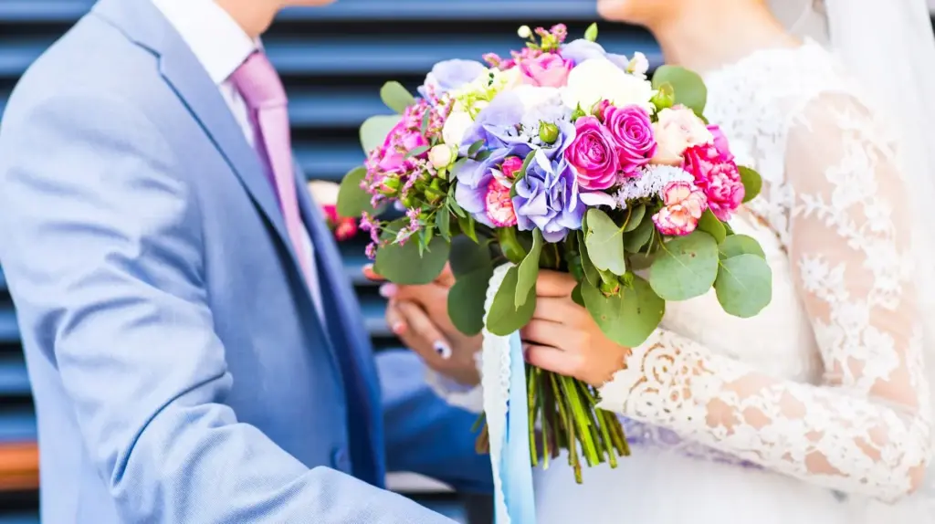 Close-up of couple with bright, seasonal bouquets
