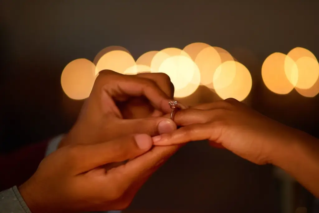 Close-up of hands or rings with fairy lights softly glowing nearby