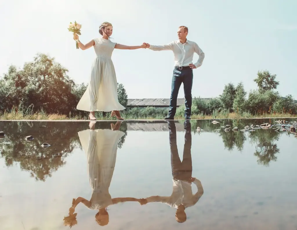 Couple holding hands with their reflections mirrored in still water