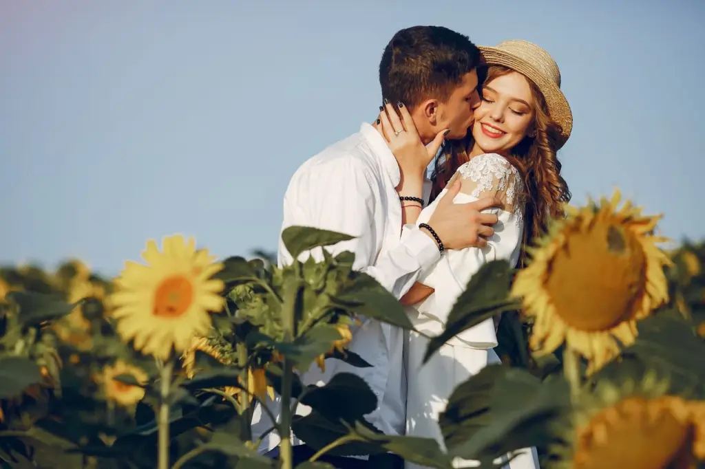 Couple sharing a kiss with sunflowers surrounding them