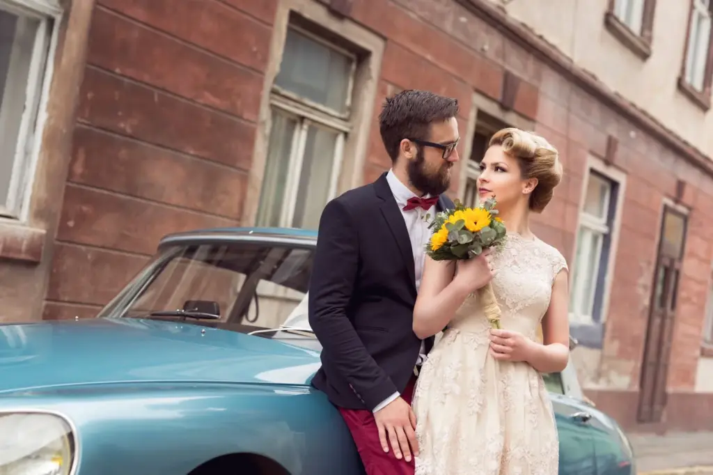 Couple standing on the ends of a classic car