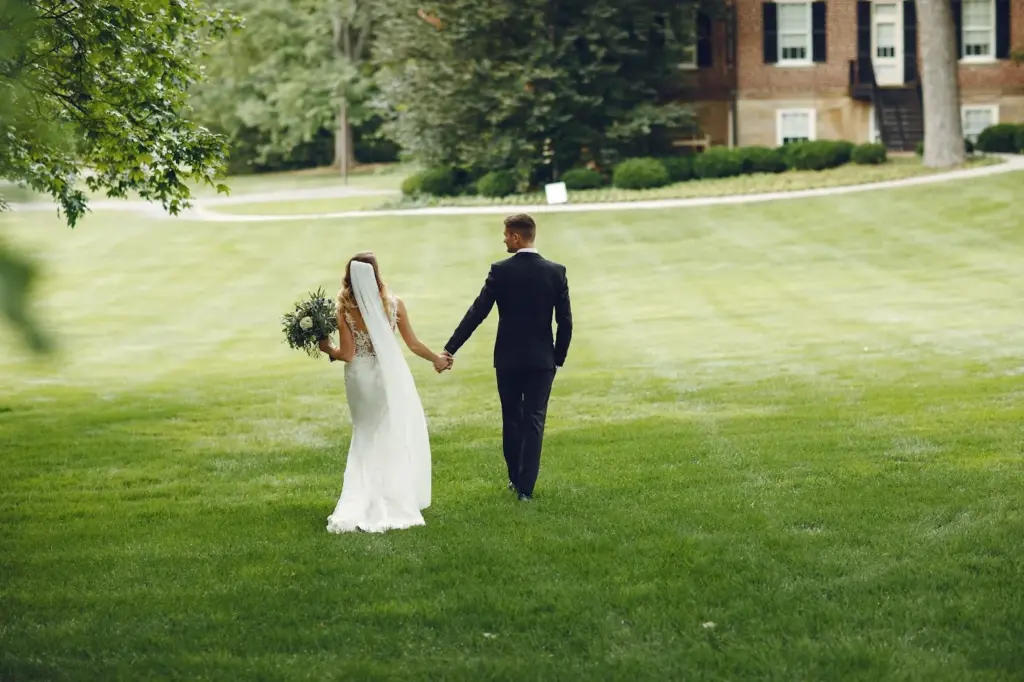 Couple walking hand-in-hand down a grassy aisle
