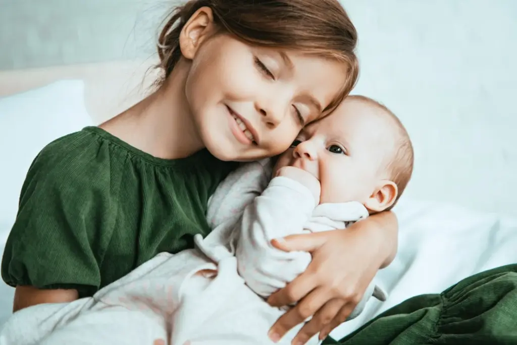Elder sibling hugging baby