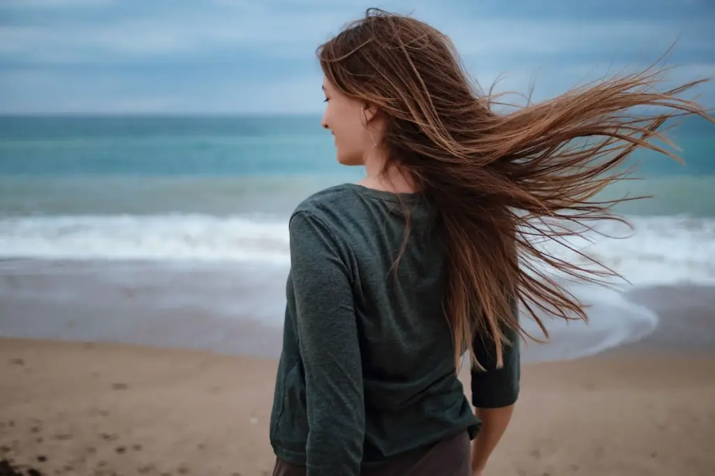 Gazing at the shoreline with wind-blown hair