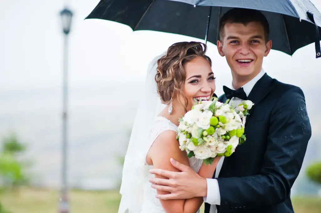 Groom holding bride in light rain