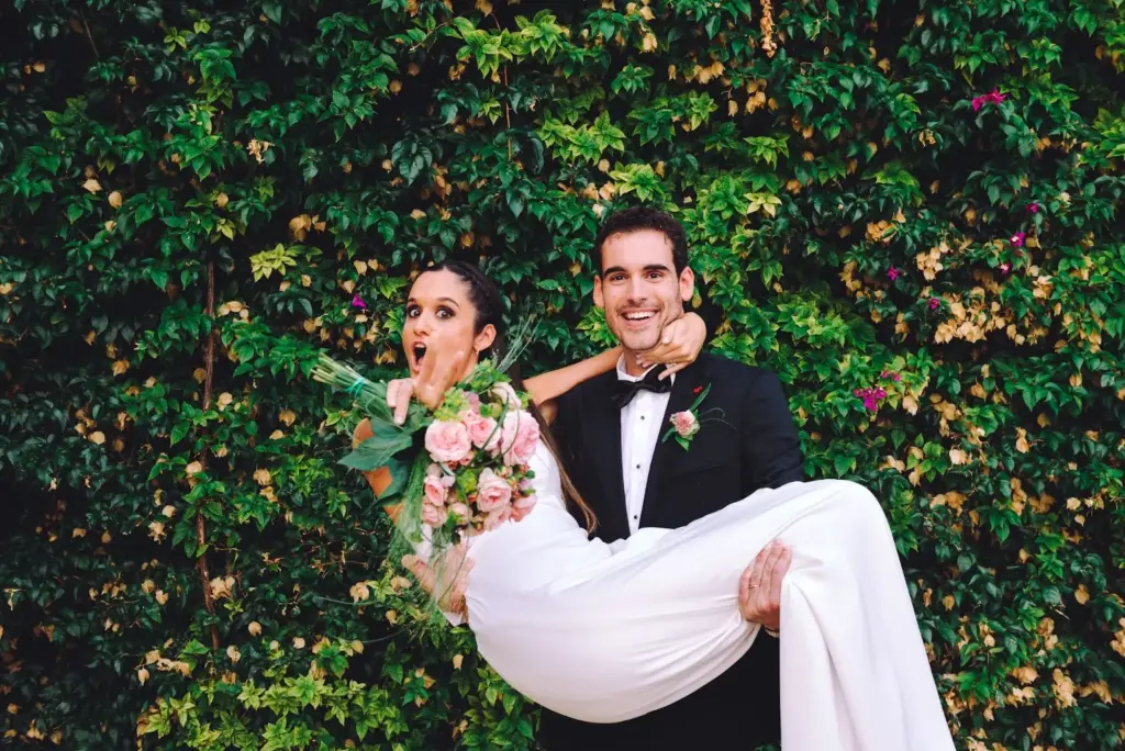 Groom lifting bride in leaf pile