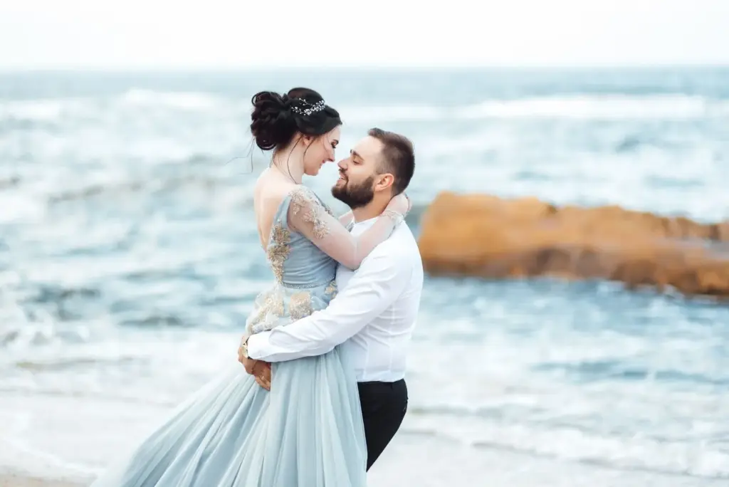 Groom lifting bride with sea in background