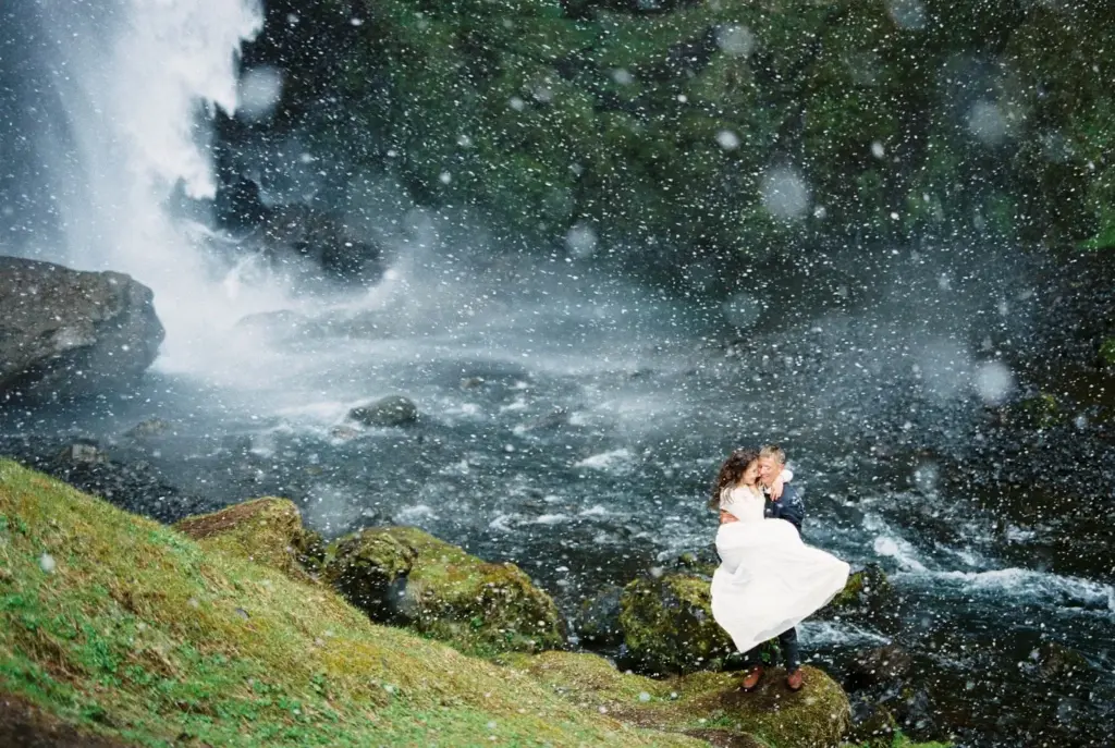 Groom lifting bride with waterfall behind