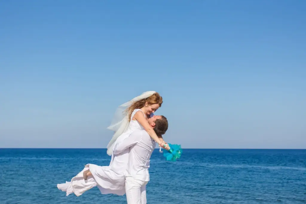 Groom lifting the bride against a vivid blue sky