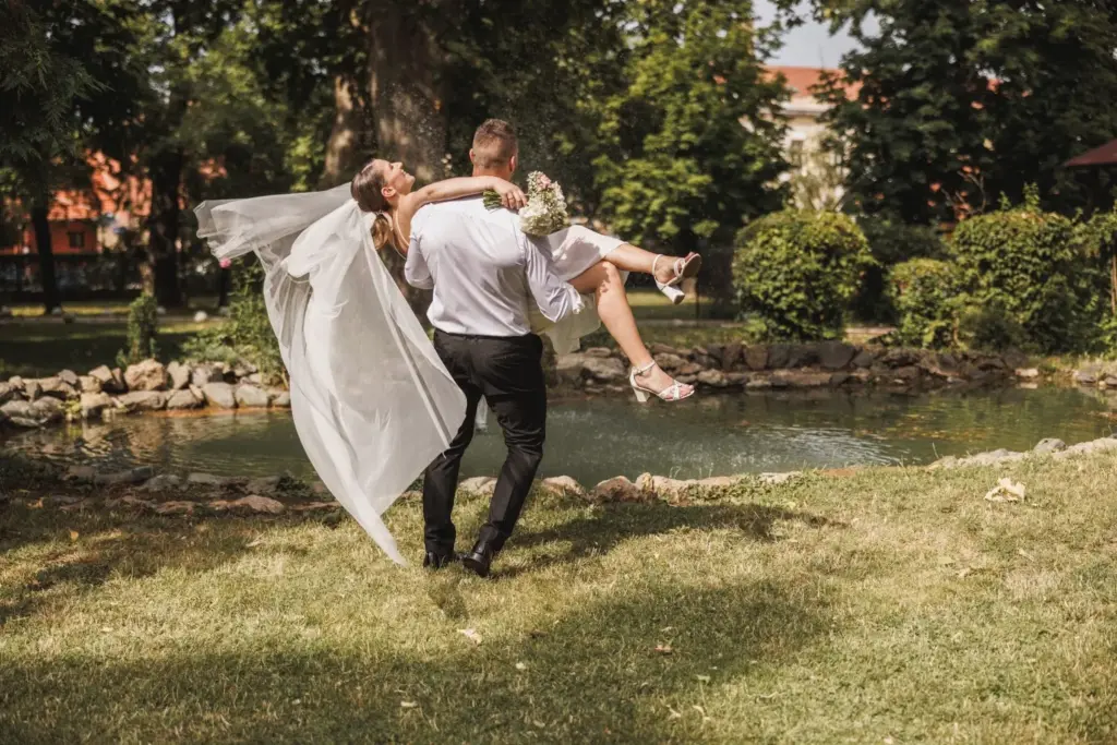 Groom lifting the bride with the lake behind