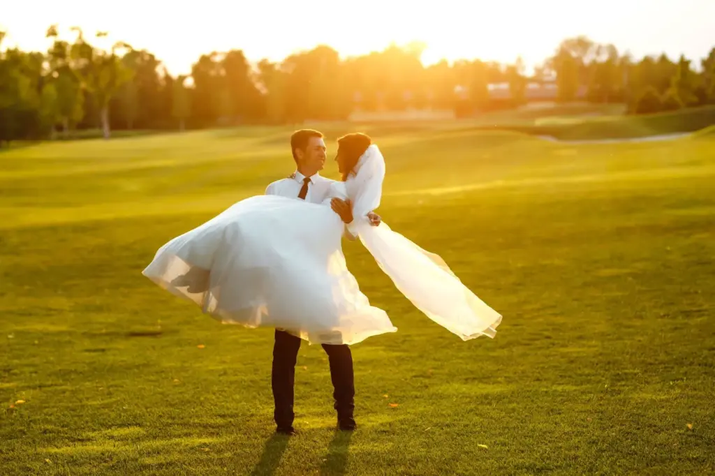 Groom lifting the bride with the sun setting behind