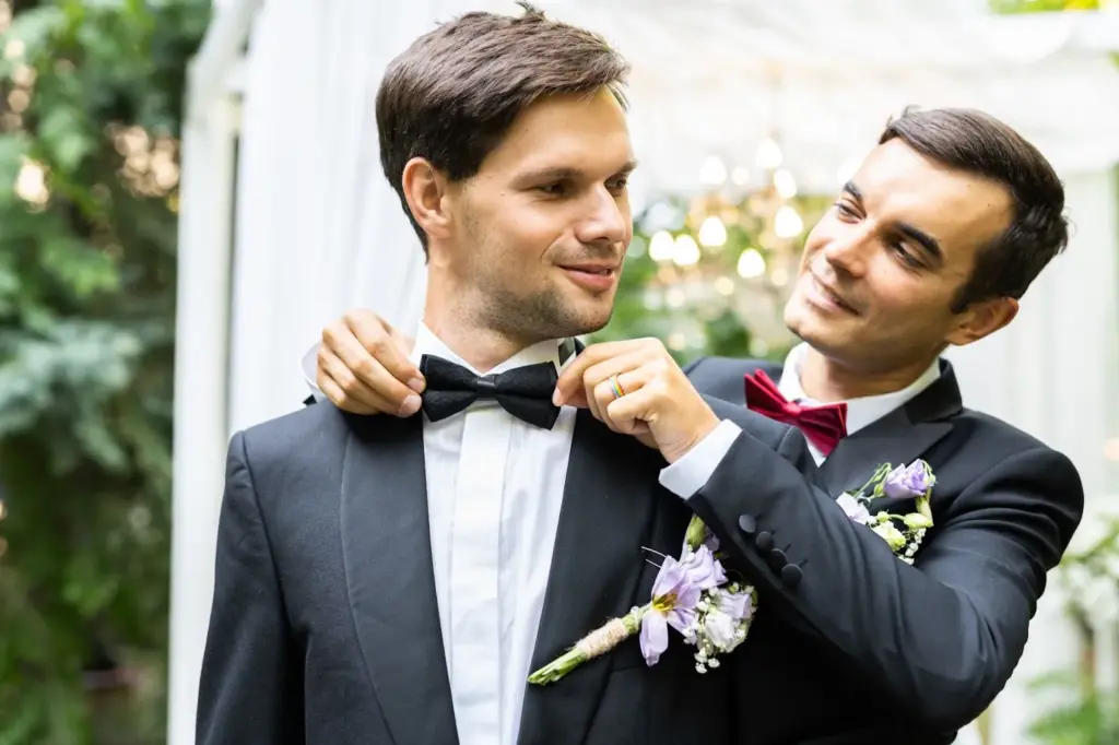 Groomsmen laughing while fixing ties or suspenders