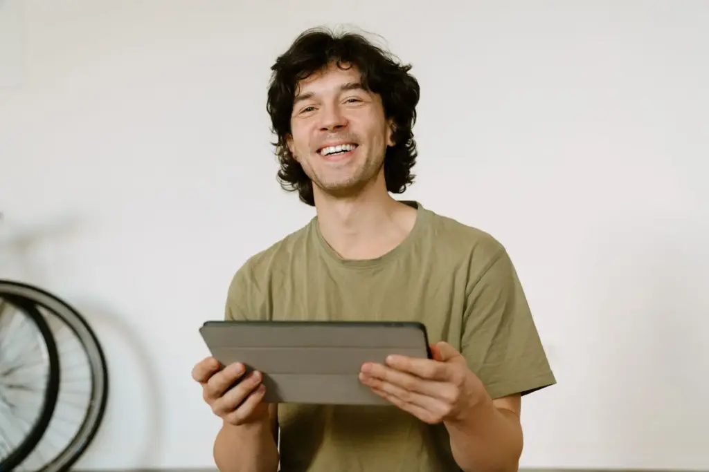 Holding a tablet and smiling towards the camera