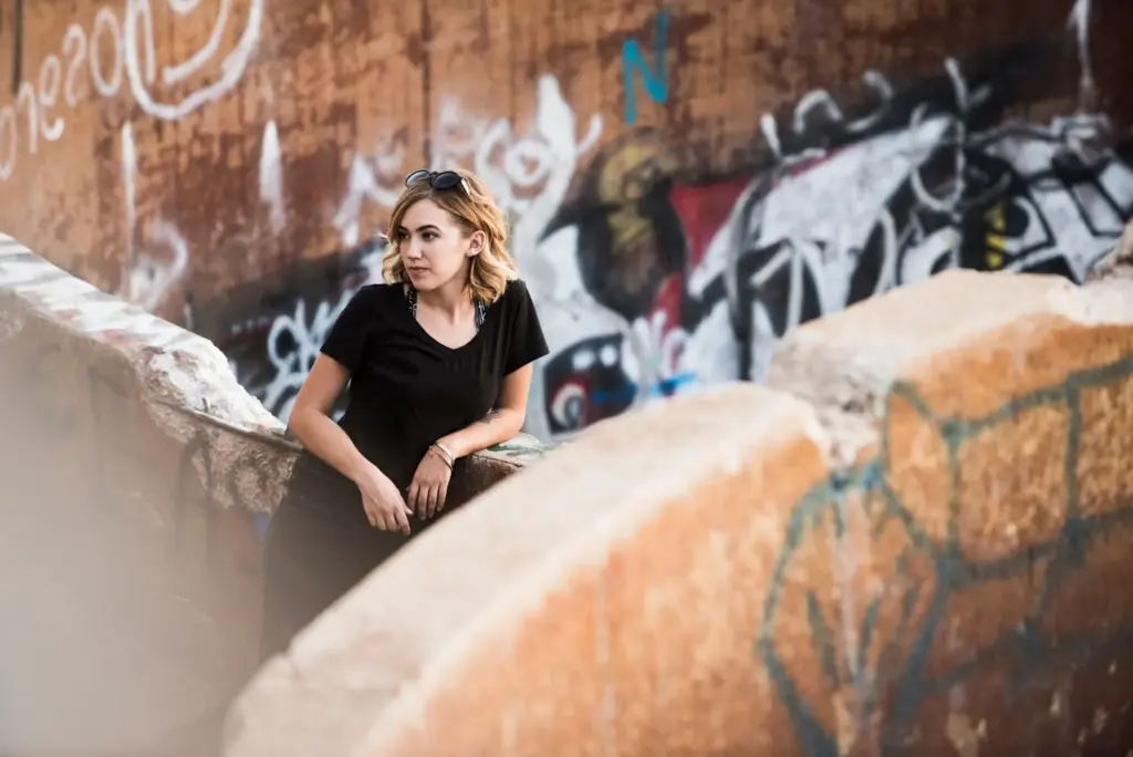 Leaning against a graffiti wall, casual cool