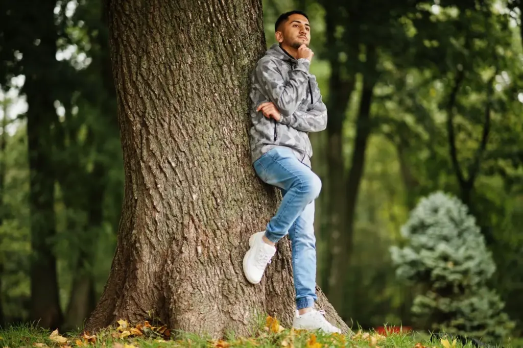 Leaning against a tall tree with bright eyes