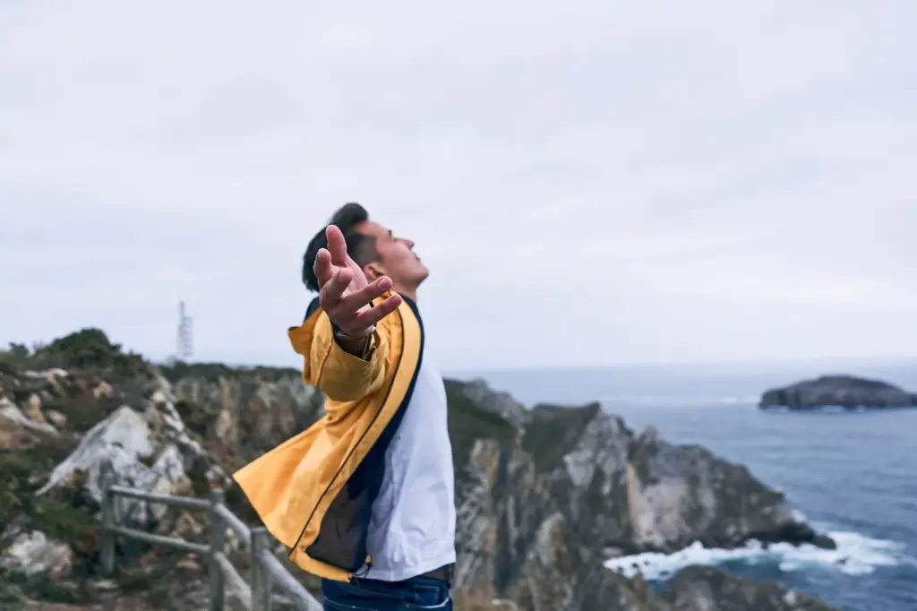 Standing at the cliff’s edge with arms spread wide