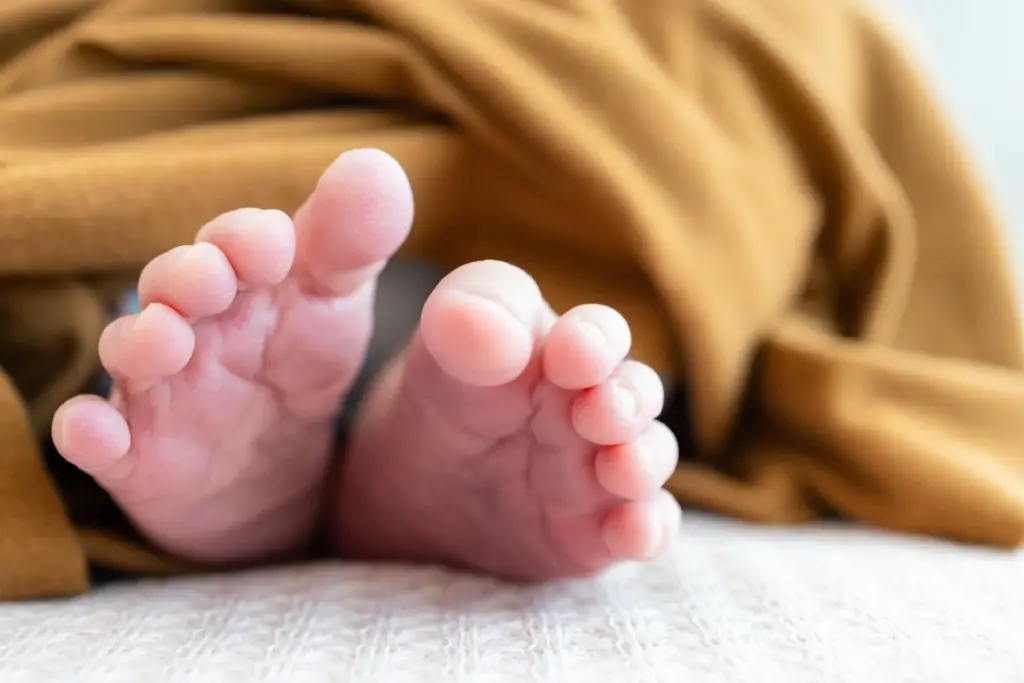 The newborn with his tiny feet on the blanket