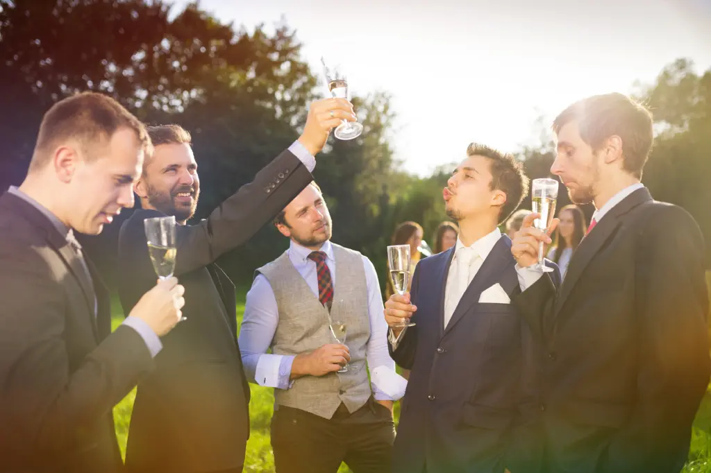 20+ Creative Group Wedding Photo Ideas for Family and Friends 25 Groom With Four Happy Groomsmen Toasting At The Wedding Reception Outside
