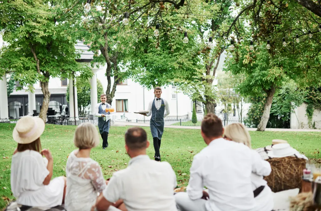 20+ Creative Group Wedding Photo Ideas for Family and Friends 71 Waiters Serving Drinks to Guests at a Relaxed Outdoor Celebration
