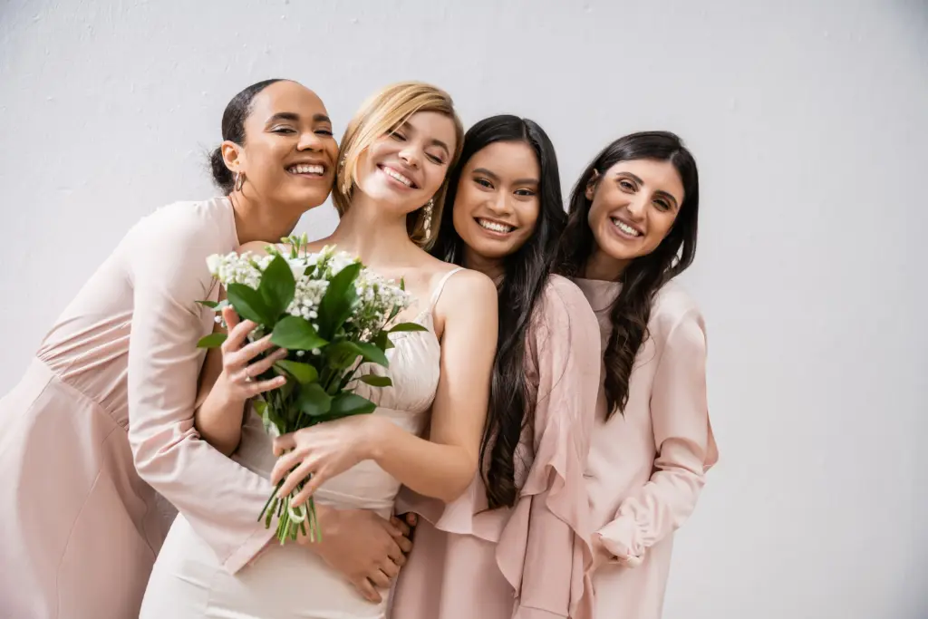 20+ Creative Group Wedding Photo Ideas for Family and Friends 42 Positivity, cheerful interracial bridesmaids hugging happy bride in wedding dress