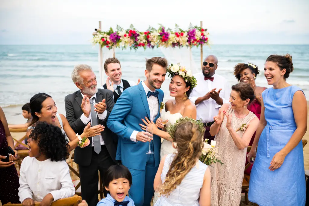 20+ Creative Group Wedding Photo Ideas for Family and Friends 36 Newlyweds Honored by a Circle of Smiles, Cheers, and Ocean Breeze